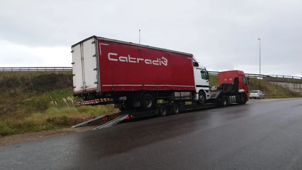 Camión rojo siendo transportado sobre plataforma de remolque.
