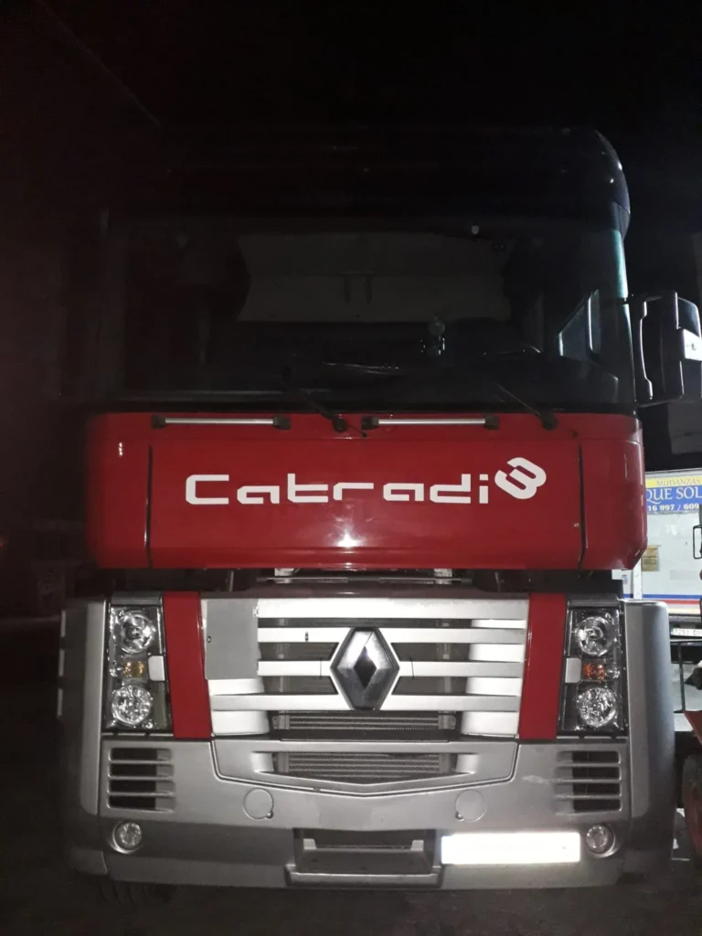 Frontal de un camión rojo "Catradi" estacionado de noche.