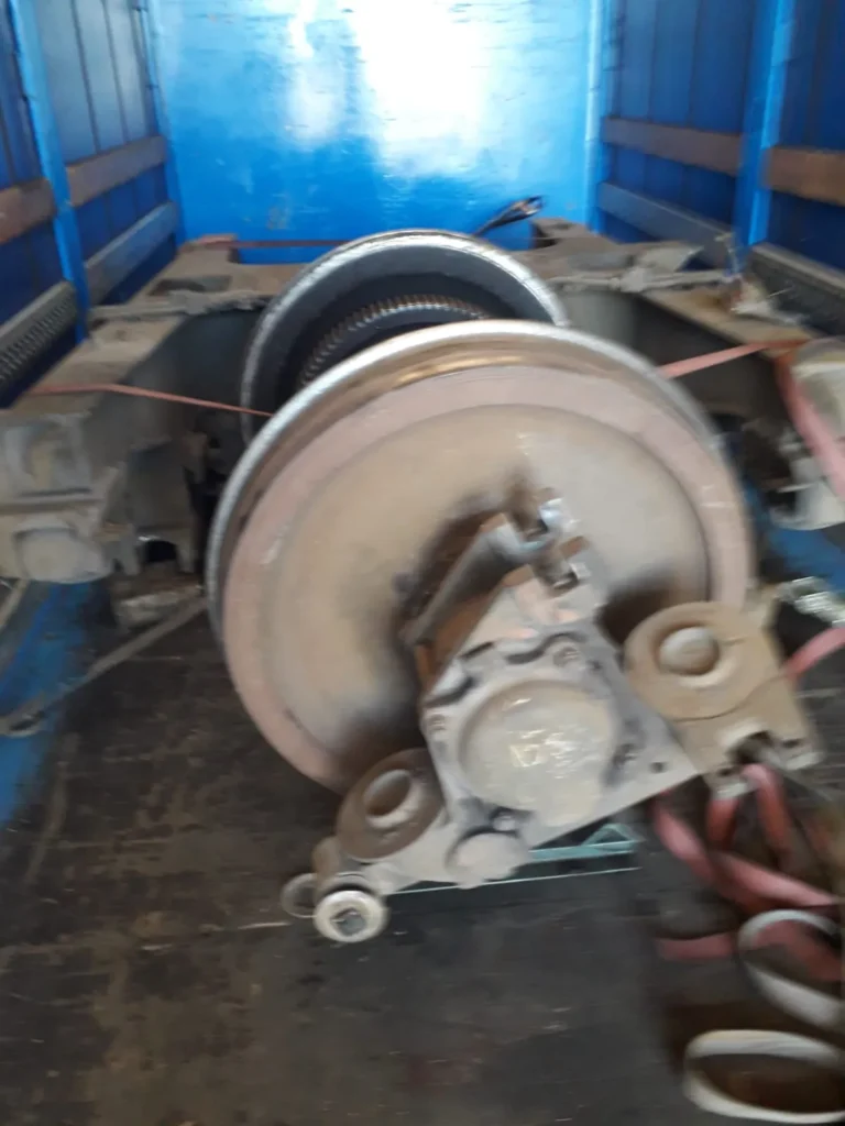 Eje de tren asegurado dentro de un camión con paredes azules.
