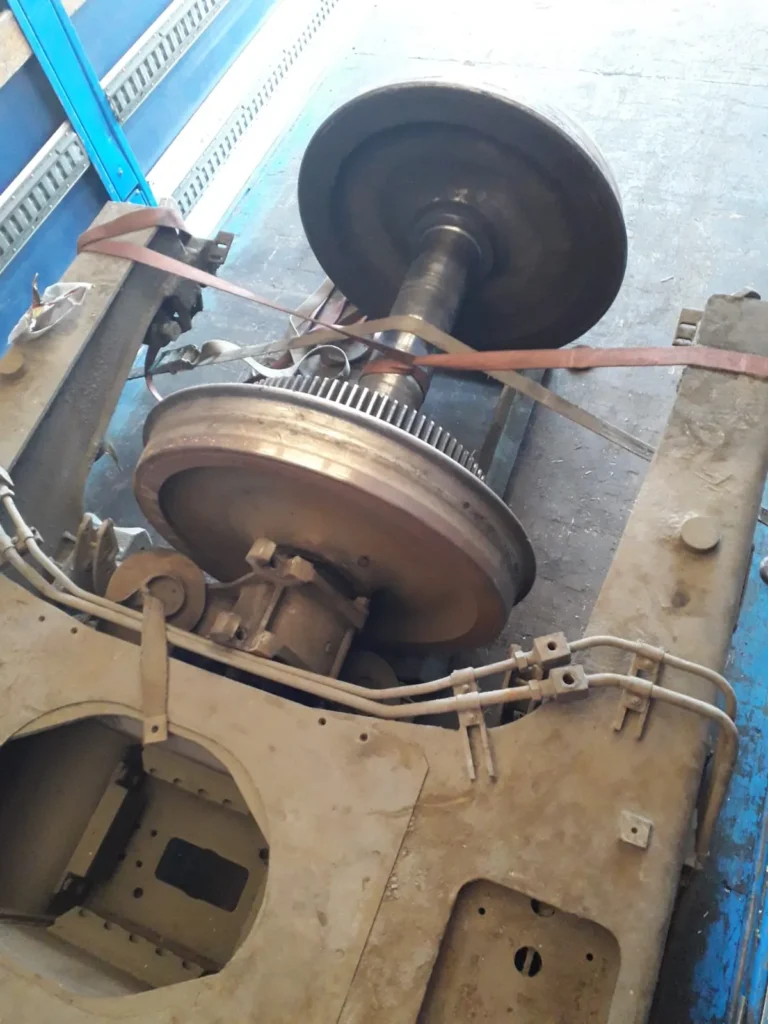 Eje y chasis de tren asegurado dentro de un camión azul.