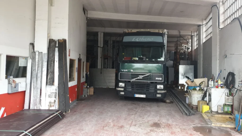 Camión verde "Volvo" estacionado dentro de un taller industrial.