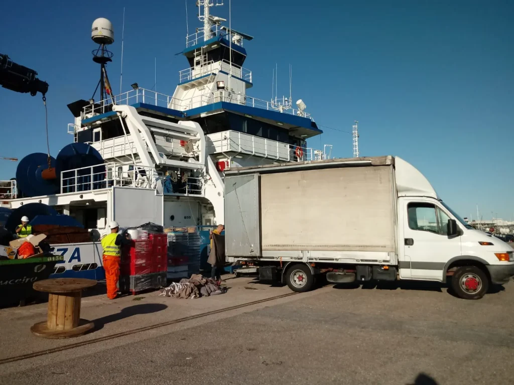 Trabajadores descargando materiales de un camión hacia el barco "Eza".