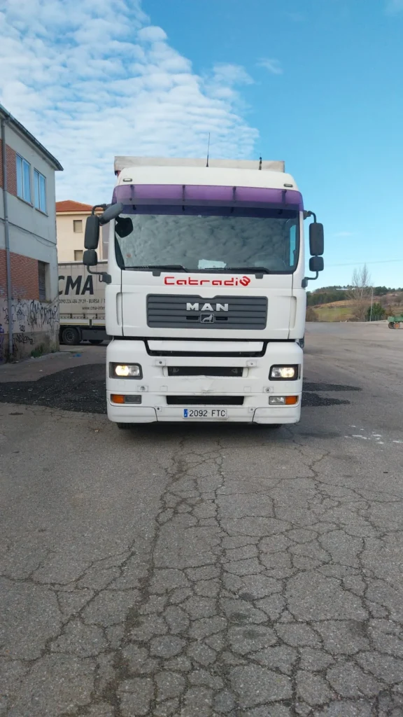 Frontal de camión blanco "Catradi" estacionado en un patio asfaltado.